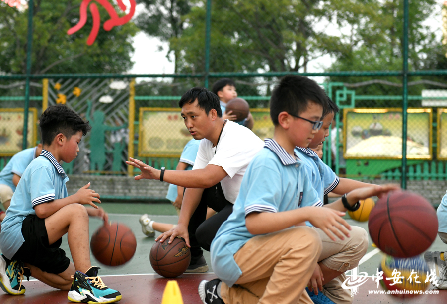 篮球场上，孩子们在体育老师带领下练习运球。.jpg