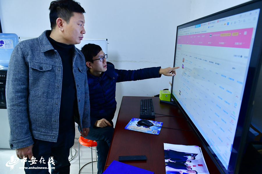 1、杨道林（左）在办公室里查看各个网店的销售数据.jpg